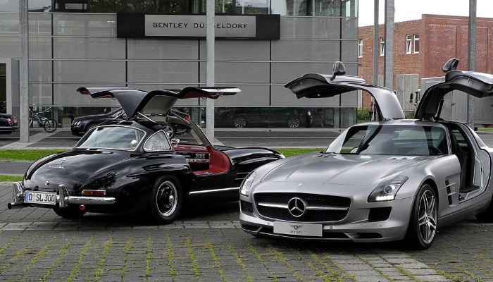 A Black Mercedes-Benz 300SL Gullwing with doors open next to. modern Mercedes gullwing in silver - iconic classic car designs